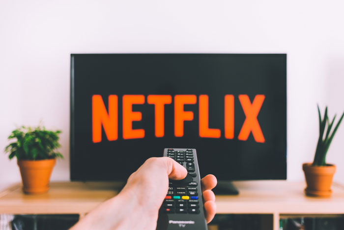 remote control pointing at a TV with Netflix logo