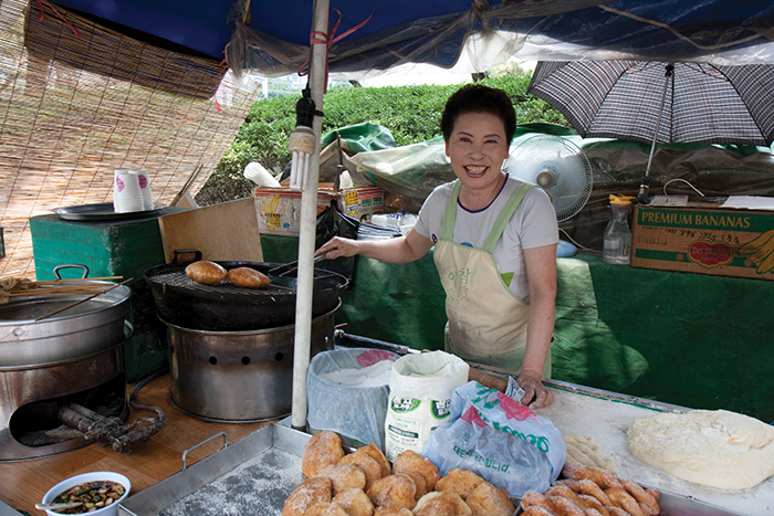 Smiling Korean woman selling doughnuts on the street