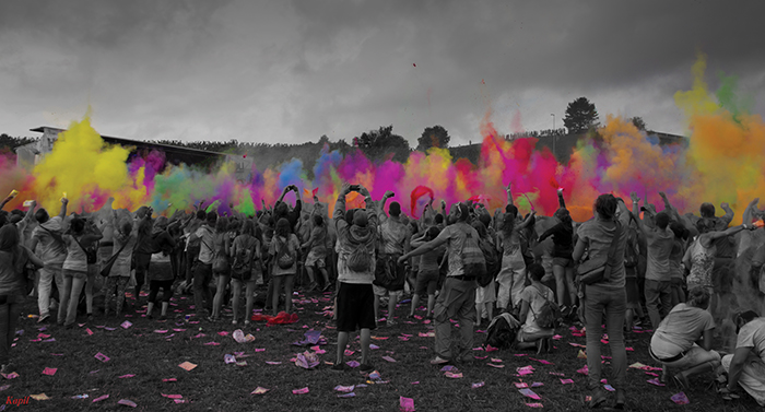 people throwing colorful powder into the air at a Holi celebration