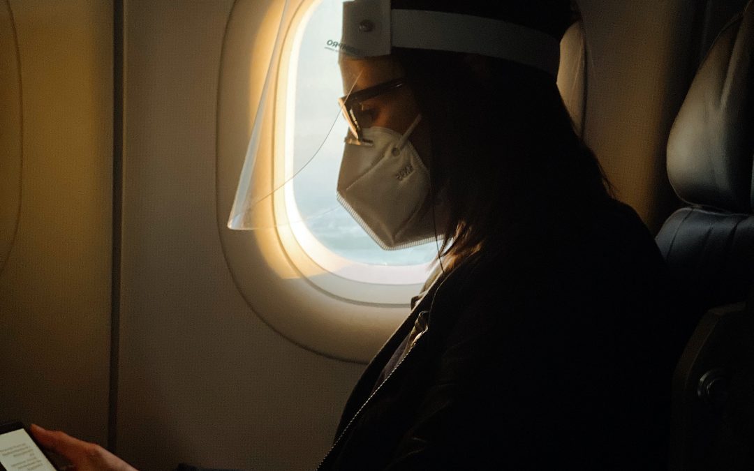 A girl wearing a mask and a face shield while on a plane