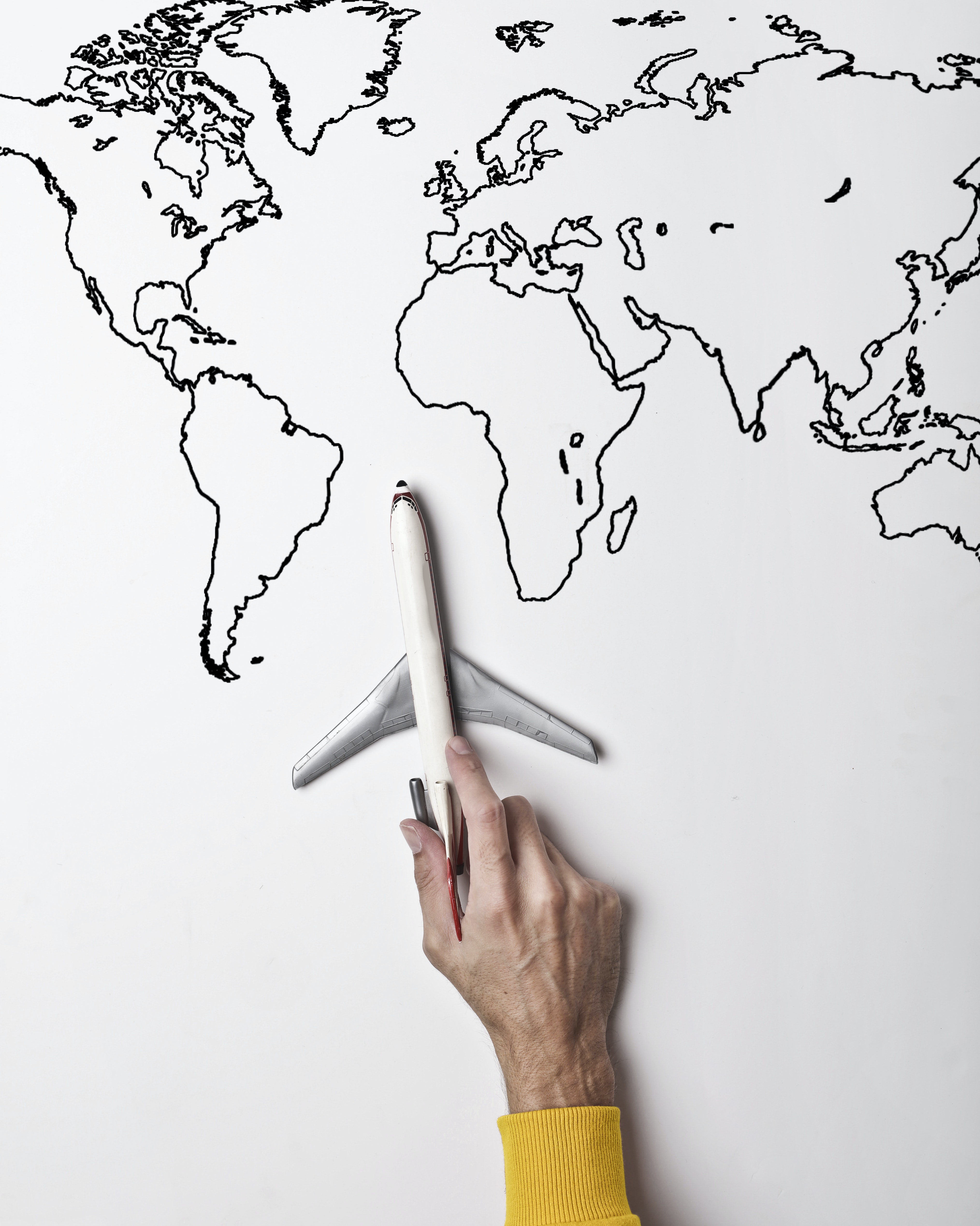A toy plane held over a black and white world map